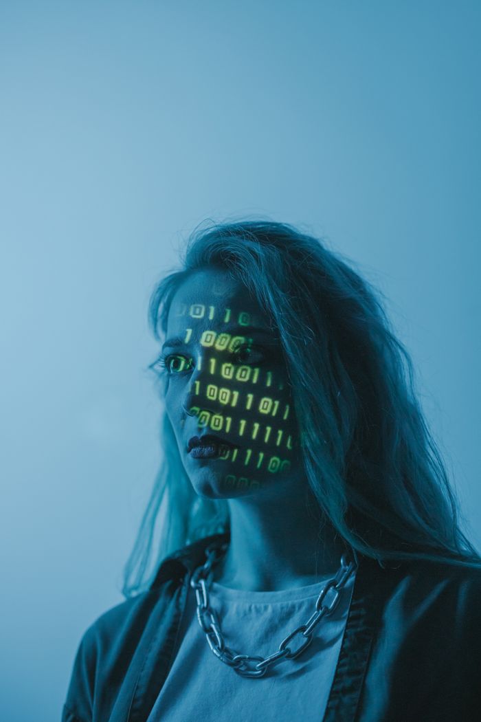 Services Stylized portrait of a woman with binary code projected on her face, evoking themes of technology and identity.
