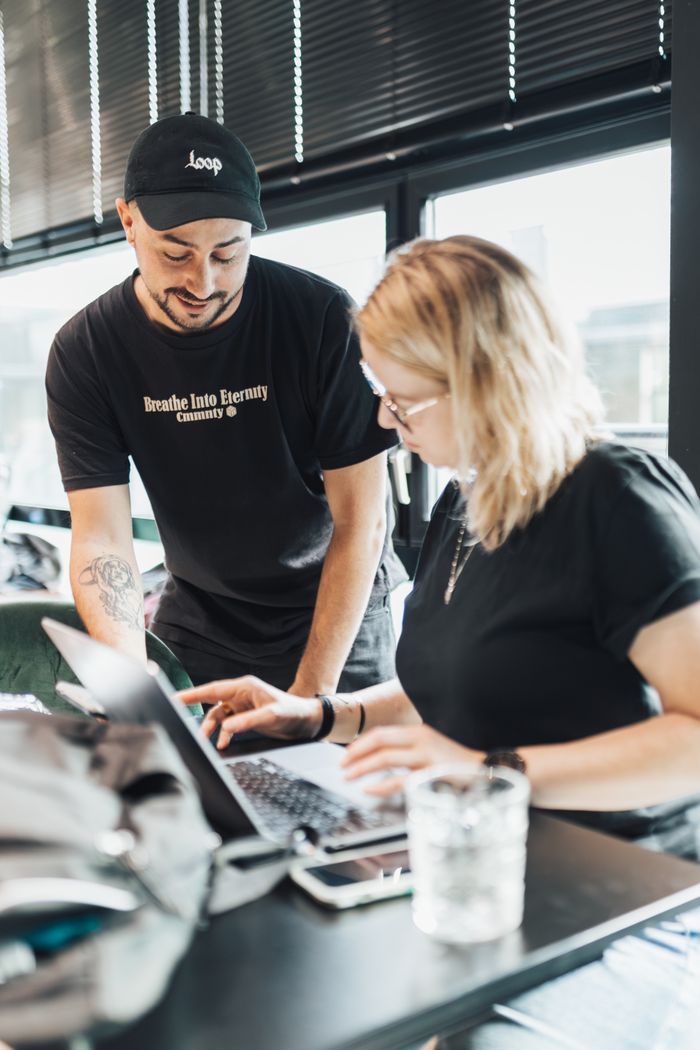 Mastering the First Impression: Your intriguing post title goes here Two colleagues work together on a laptop in a bright, modern office setting, showcasing teamwork and productivity.
