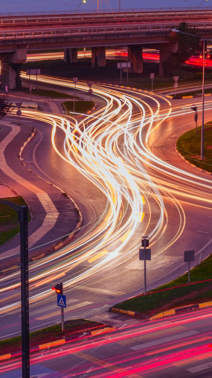 Services A vibrant long exposure photo capturing light trails at an urban intersection during nighttime.
